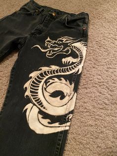 a pair of black jeans with a dragon painted on them