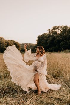 a woman in a white dress sitting on the ground with her arms outstretched and legs spread out