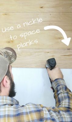 a man holding a remote control in front of a wooden sign that says use a nickle to space planks