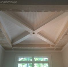 an empty room with white walls and wooden beams on the ceiling is shown in front of a window