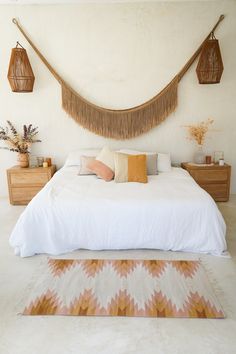 a bed with white sheets and pillows in a bedroom next to two hanging baskets on the wall