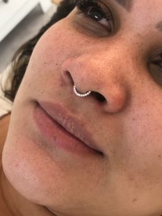 a close up of a person with a nose ring on their nose and one eye open