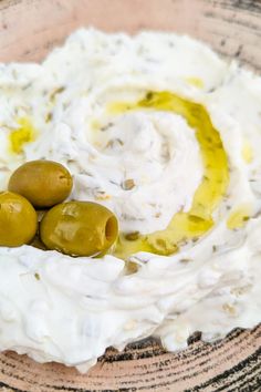 some olives are sitting in a bowl with white cream