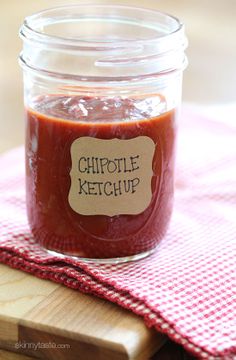 a jar of chipotle ketchup sitting on top of a wooden cutting board