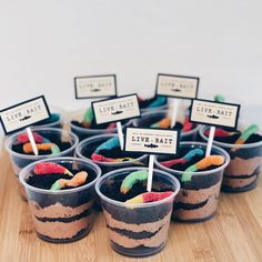 there are cupcakes that have been placed in cups with candy on sticks sticking out of them