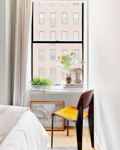 a bedroom with a bed, window and chair in it's corner area next to the windowsill