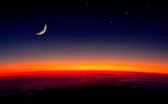 the moon is seen above the clouds at night