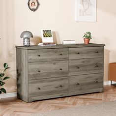 a room with a dresser, potted plants and pictures on the wall