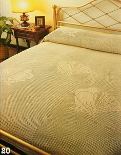 a bed with a white bedspread sitting next to a night stand and lamp