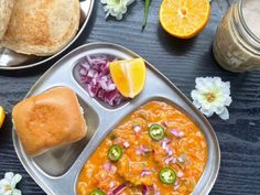 a metal tray filled with food next to orange slices and other foods on a table