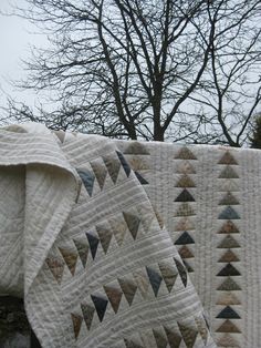 an elephant is standing next to two quilts on a clothes line with trees in the background