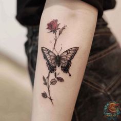 a woman's arm with a butterfly and rose tattoo on it