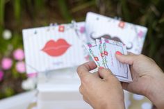 a person holding up some cards with lipstick on them