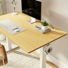 a computer desk with a monitor, keyboard and mouse on it in front of a plant