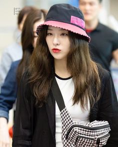 a young woman with long hair wearing a hat and black jacket is walking down the street