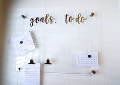 there is a bulletin board that says goals to do and two magnets on the wall