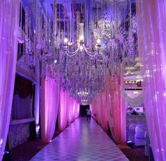 a long hallway decorated with pink curtains and chandeliers