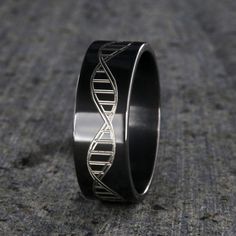 Fun 8mm Wide DNA Strand Ring with an ultra round deluxe comfort fit. This is a two-tone ring with black and silver. The DNA strand is milled into the solid black zirconium. This ring is custom made to order.•Black Zirconium DNA Ring•Deluxe Comfort Fit Design Black Titanium Round Jewelry, Black Titanium Anniversary Rings, Black Titanium Jewelry As Gift, Black Titanium Jewelry Gift, Formal Black Titanium Jewelry, Minimalist Black Hypoallergenic Rings, Modern Black Tungsten Carbide Jewelry, Modern Black Titanium Jewelry, Dna Ring