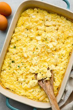 a casserole dish with eggs in it and a wooden spoon on the side