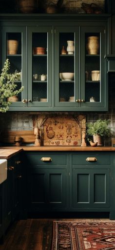 a kitchen with dark green cabinets and wooden floors, an area rug on the floor