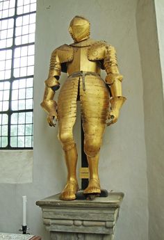 a statue of a man in armor standing next to a window