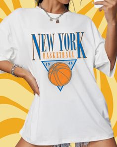 a woman wearing a new york basketball t - shirt and holding a drink in her hand