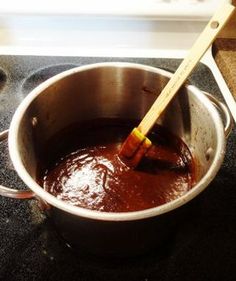 a wooden spatula in a saucepan filled with red liquid on top of a stove