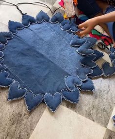 someone is making a heart - shaped piece of denim fabric with scissors and thread on the floor