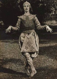 an old black and white photo of a woman dressed in medieval clothing with her arms outstretched