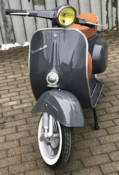 a scooter parked on the side of a brick road next to a fence