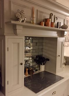 a stove top oven sitting inside of a kitchen next to white cupboards and drawers