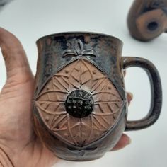 a hand holding a coffee mug with designs on it