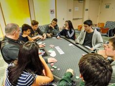 a group of people sitting around a table playing cards