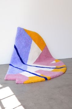 a multicolored rug sitting on top of a cement floor next to a white wall