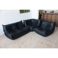 two black leather couches sitting on top of a hard wood floor