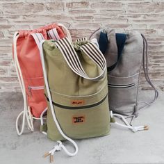 three drawstring bags sitting next to each other in front of a brick wall