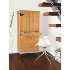 a wooden cabinet sitting on top of a hard wood floor next to a white chair