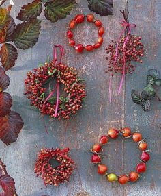 several wreaths and berries are arranged on a wooden surface next to some leaves,