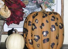 two pumpkins sitting on top of a table next to flowers and other items in vases