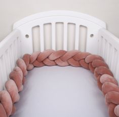 a white crib with pink pillows on it's sides and a pillow in the middle