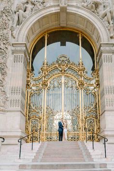 a bride and groom are standing on the stairs in front of an ornate door at their wedding