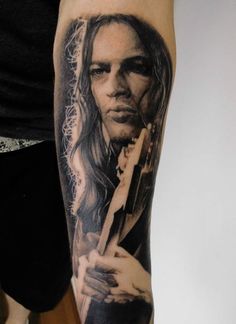 a woman holding a guitar tattoo on her arm