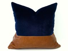 a blue and brown pillow on a white background with a black leather accented cushion