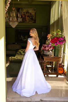 a woman in a white wedding dress standing on the steps looking at something off to the side