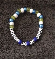 a beaded bracelet with words and letters on it, sitting on a black surface