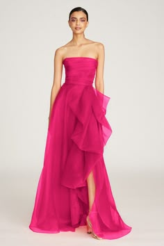 Our bestselling Teresa gown is back in dazzling zinnia color. It's sculpted in pebble organza—a weightless and high-quality fabric woven to give your style movement and bounce. This radiant piece comes strapless and features a draped bodice, front slit accent, and a cascading ruffled skirt. Click here for all available colors. Strapless Neckline A Line Silhouette Non-Stretch Floor Length REF: 8817572 Red Green Dress, Train Christmas, Draped Gown, Gown Elegant, Draped Bodice, Drape Gowns, Dresses Formal Elegant, Looks Party, Evening Gowns Elegant