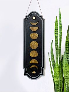 a black and gold clock hanging on a wall next to a potted plant