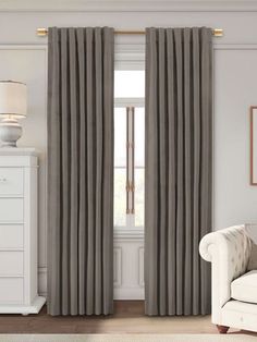 a living room with a white couch and curtains in grey colors on the windowsill