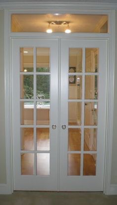 an empty room with two white doors and wood flooring on either side of the door