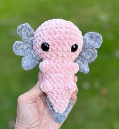 a hand holding a small pink and gray stuffed animal